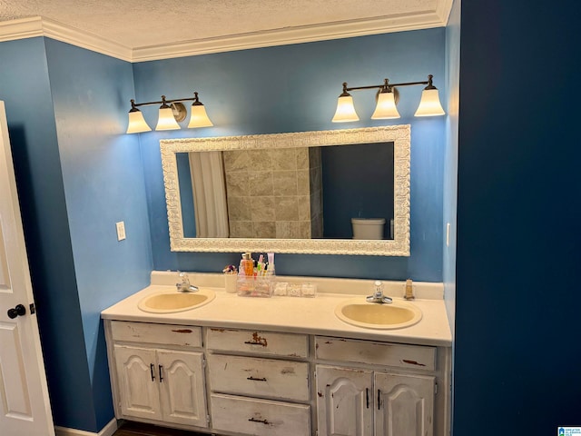 bathroom featuring toilet, vanity, a textured ceiling, and ornamental molding