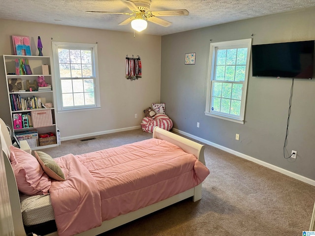 bedroom with multiple windows, ceiling fan, carpet floors, and a textured ceiling