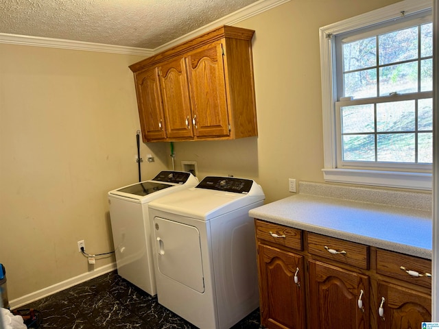 clothes washing area featuring a textured ceiling, washer and dryer, cabinets, and crown molding