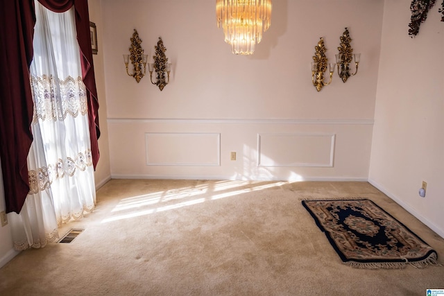 carpeted empty room with a chandelier