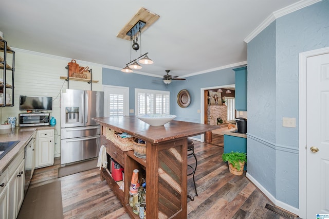 kitchen with dark hardwood / wood-style flooring, stainless steel appliances, and crown molding