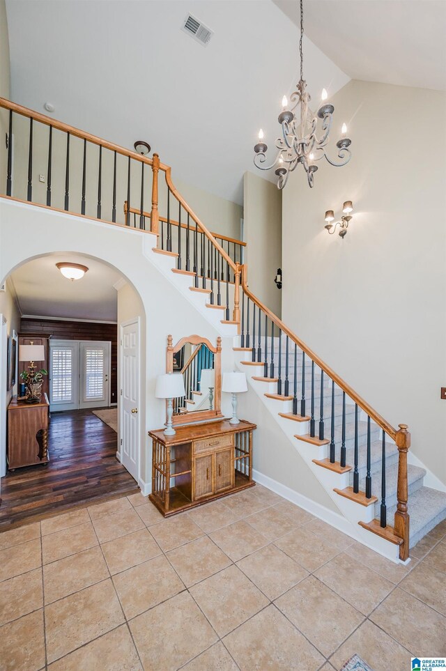 stairway featuring hardwood / wood-style flooring, high vaulted ceiling, and a notable chandelier