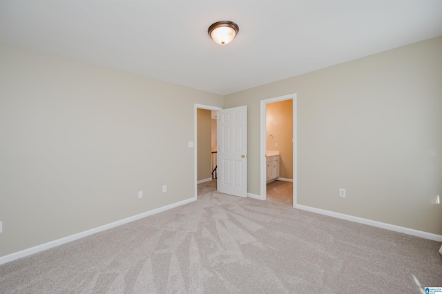 unfurnished bedroom with ensuite bathroom and light colored carpet