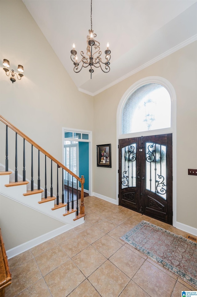 tiled entryway with crown molding, french doors, high vaulted ceiling, and a chandelier