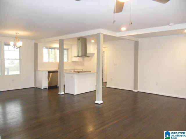 unfurnished living room featuring ceiling fan with notable chandelier and dark hardwood / wood-style floors