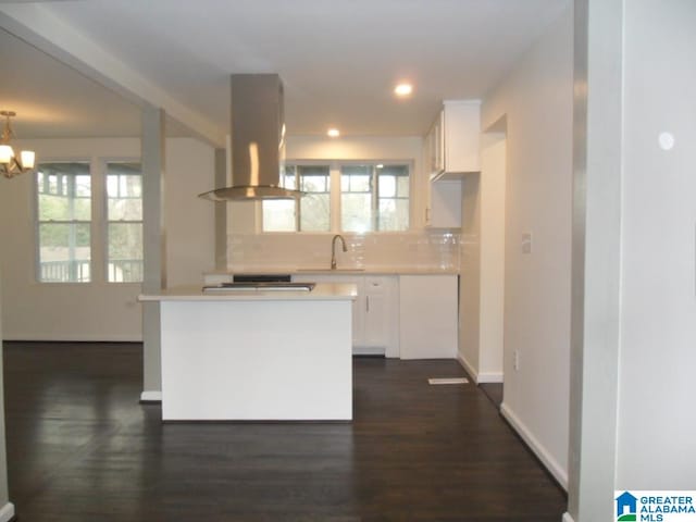 kitchen with tasteful backsplash, island exhaust hood, plenty of natural light, and white cabinets