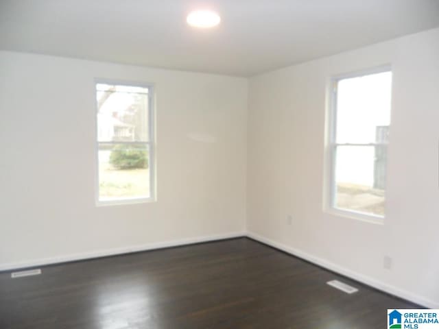 empty room with dark hardwood / wood-style floors and a healthy amount of sunlight