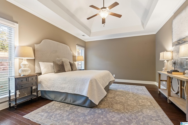 bedroom with dark hardwood / wood-style floors, ceiling fan, crown molding, and a tray ceiling