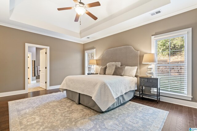 bedroom featuring a raised ceiling, ceiling fan, dark hardwood / wood-style floors, and ornamental molding