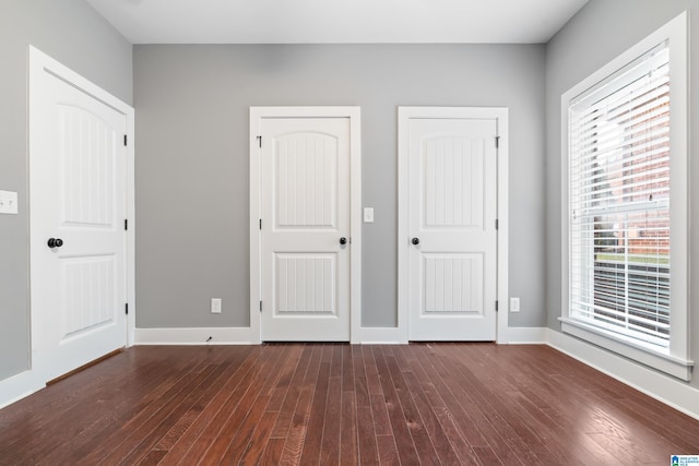 unfurnished bedroom with two closets and dark hardwood / wood-style floors