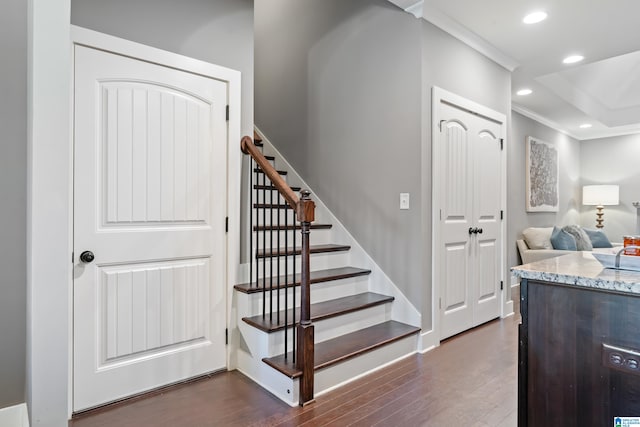 stairs with wood-type flooring and crown molding