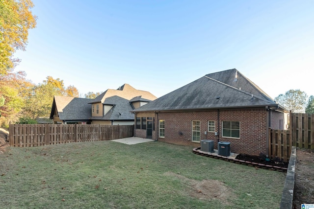 rear view of property featuring a lawn, a patio area, and central AC unit