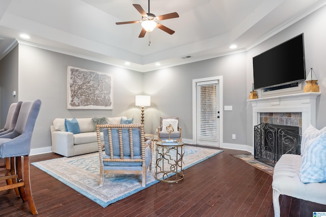 living room featuring a tiled fireplace, dark hardwood / wood-style flooring, and ornamental molding