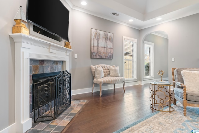 living area with dark hardwood / wood-style flooring, ornamental molding, and a tile fireplace