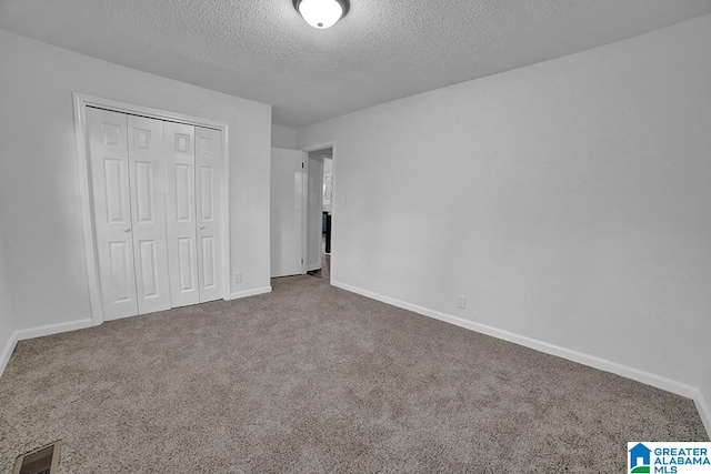 unfurnished bedroom featuring carpet floors, a textured ceiling, and a closet