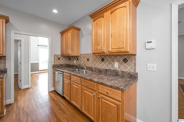 kitchen featuring decorative backsplash, dark hardwood / wood-style flooring, dark stone counters, sink, and dishwasher