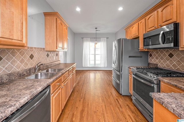 kitchen with light wood-type flooring, backsplash, stainless steel appliances, sink, and decorative light fixtures