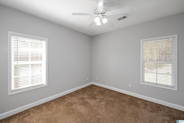 carpeted empty room with a wealth of natural light and ceiling fan