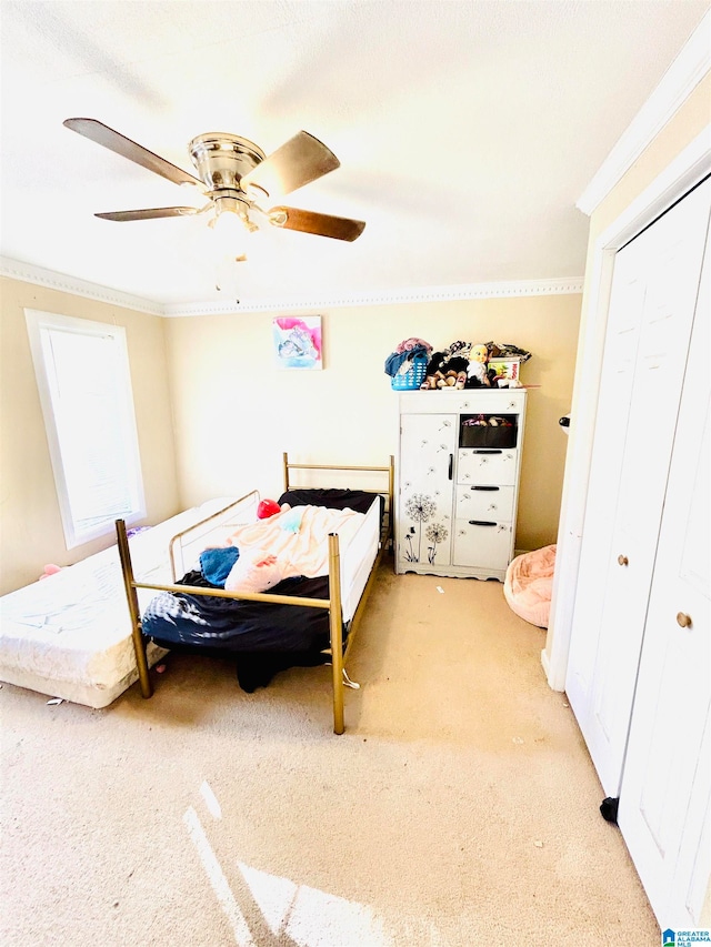 bedroom with ceiling fan, ornamental molding, light carpet, and a closet