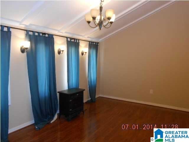 spare room with a chandelier, crown molding, and dark wood-type flooring