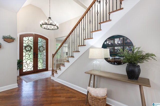 foyer with french doors, an inviting chandelier, high vaulted ceiling, and dark wood-type flooring