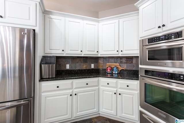 kitchen with tasteful backsplash, white cabinetry, dark stone counters, and stainless steel appliances