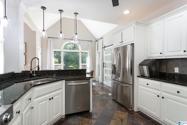 kitchen featuring appliances with stainless steel finishes, sink, decorative light fixtures, dark stone countertops, and white cabinetry