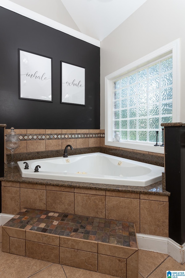 bathroom with tile patterned floors, a relaxing tiled tub, and lofted ceiling