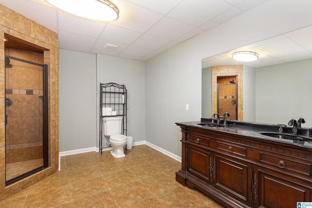 bathroom featuring a paneled ceiling, vanity, a shower with door, tile patterned flooring, and toilet