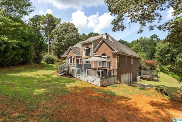 rear view of house with a lawn, a trampoline, cooling unit, a gazebo, and a deck