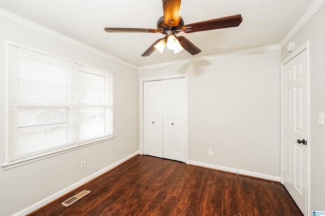 unfurnished bedroom with ceiling fan, ornamental molding, dark wood-type flooring, and a closet