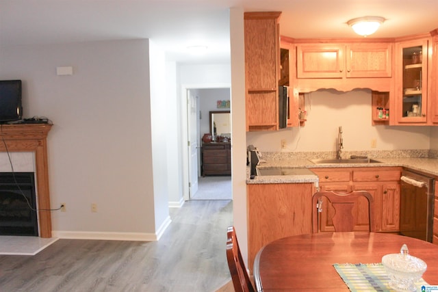 kitchen featuring sink, range, dishwasher, hardwood / wood-style flooring, and a tiled fireplace