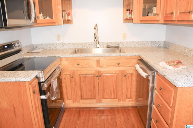 kitchen featuring light stone counters, stainless steel appliances, light hardwood / wood-style floors, and sink