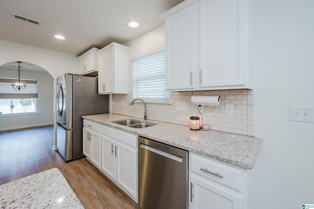 kitchen with white cabinets, sink, appliances with stainless steel finishes, and light hardwood / wood-style flooring