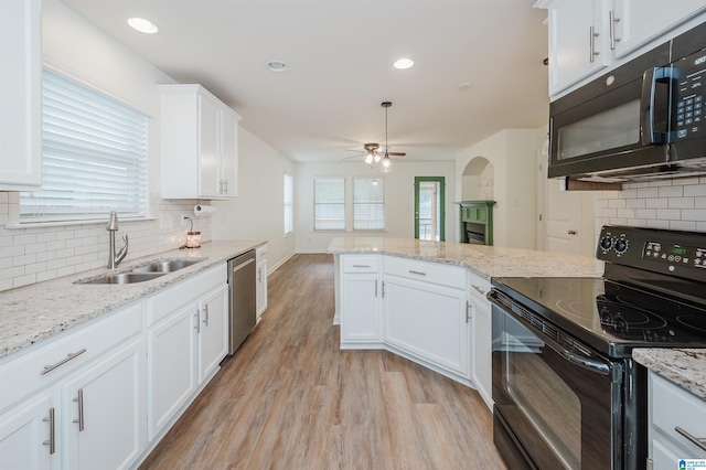 kitchen featuring white cabinetry, sink, backsplash, black appliances, and light wood-type flooring