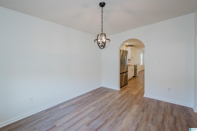 spare room with light hardwood / wood-style floors and a chandelier