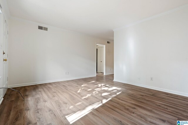 empty room featuring hardwood / wood-style flooring and ornamental molding