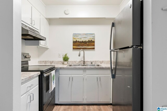 kitchen featuring white cabinetry, sink, light hardwood / wood-style flooring, and appliances with stainless steel finishes