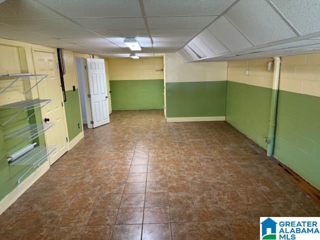 basement with a drop ceiling and tile patterned flooring