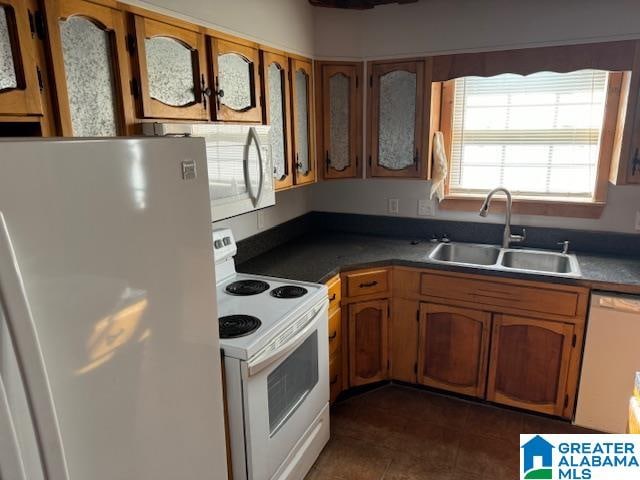 kitchen with dark tile patterned floors, white appliances, and sink