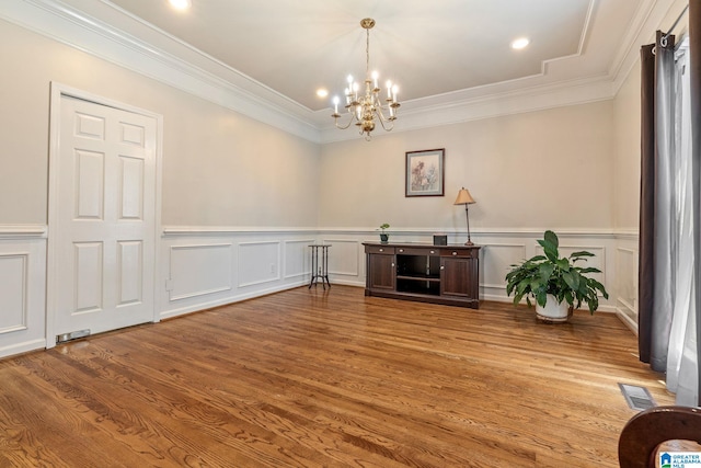 interior space with hardwood / wood-style floors, ornamental molding, and an inviting chandelier