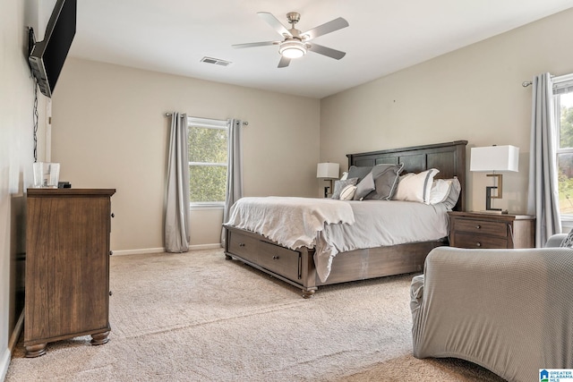 carpeted bedroom featuring multiple windows and ceiling fan