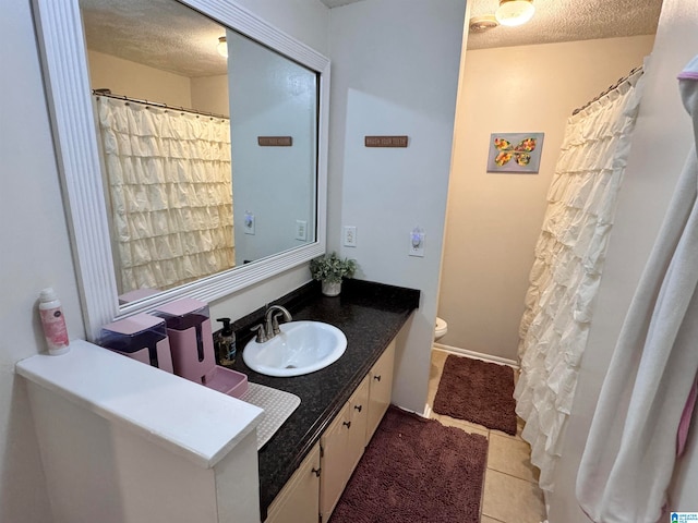 bathroom featuring tile patterned flooring, vanity, a textured ceiling, and toilet