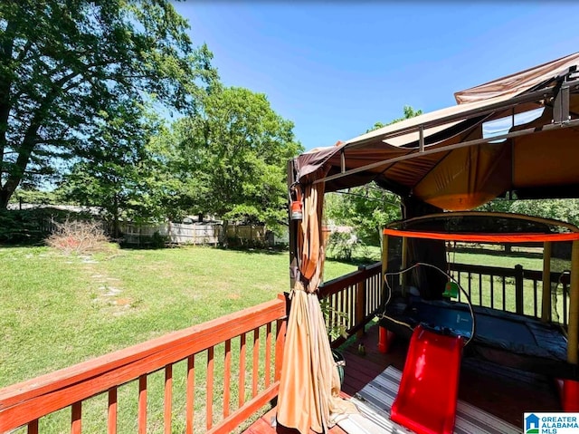 wooden deck with a yard and a trampoline