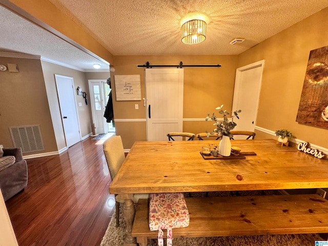 dining space featuring dark hardwood / wood-style flooring, ornamental molding, a textured ceiling, a barn door, and a notable chandelier