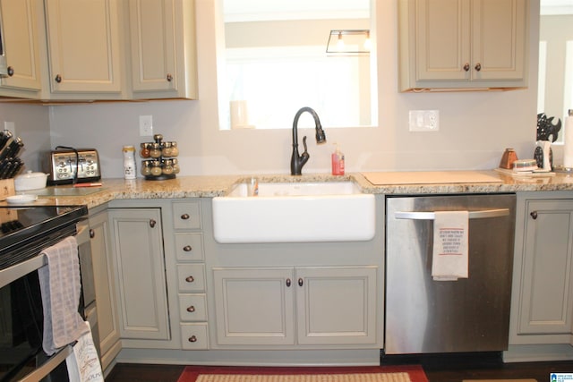 kitchen with dark hardwood / wood-style floors, light stone counters, sink, and appliances with stainless steel finishes