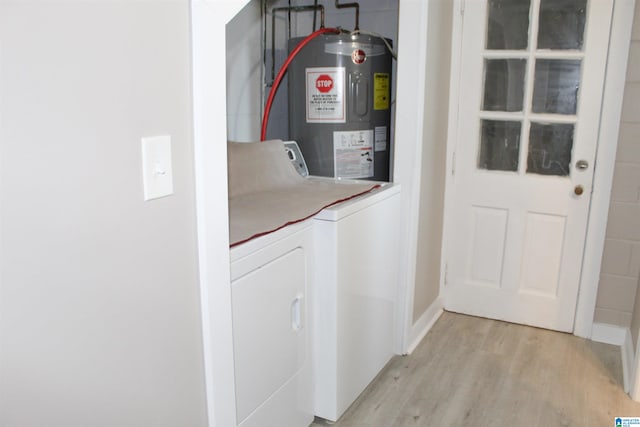 laundry room with washing machine and dryer, electric water heater, and light wood-type flooring