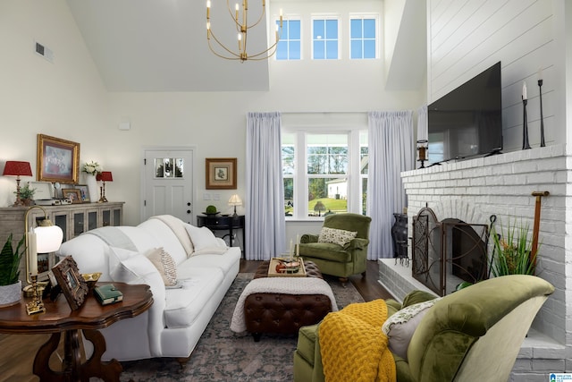 living room with a chandelier, high vaulted ceiling, a brick fireplace, and dark wood-type flooring