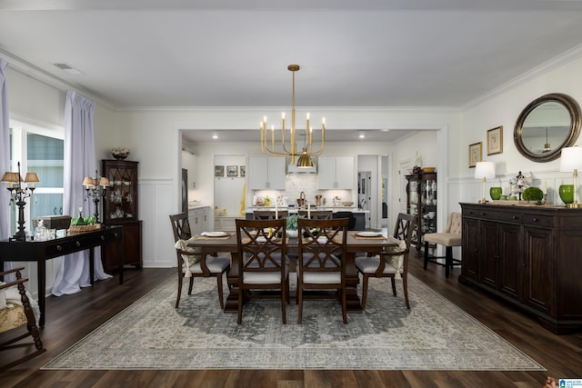 dining space with crown molding, dark wood-type flooring, and an inviting chandelier