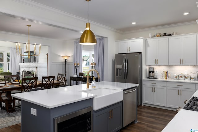 kitchen featuring stainless steel appliances, dark wood-type flooring, sink, white cabinetry, and hanging light fixtures